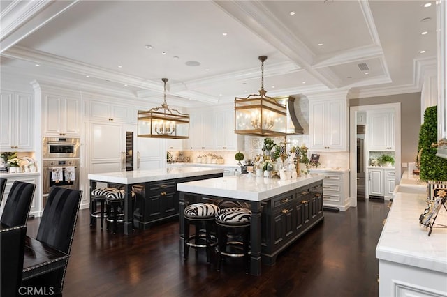 kitchen featuring white cabinetry, decorative light fixtures, a center island, a kitchen breakfast bar, and double oven