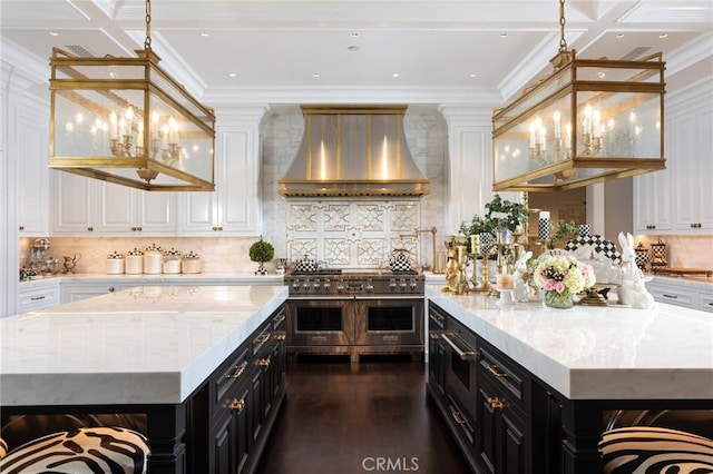 kitchen with extractor fan, white cabinetry, light stone counters, a kitchen island, and range with two ovens