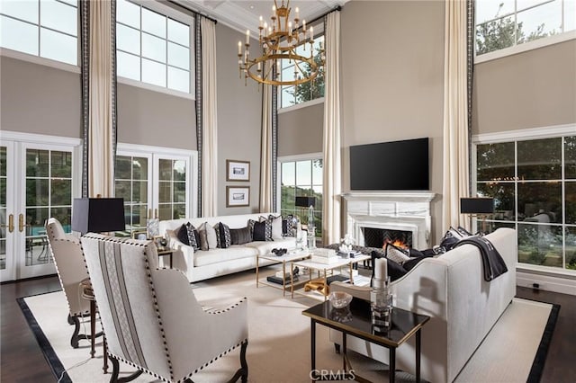 living room featuring french doors, wood-type flooring, an inviting chandelier, and a high ceiling