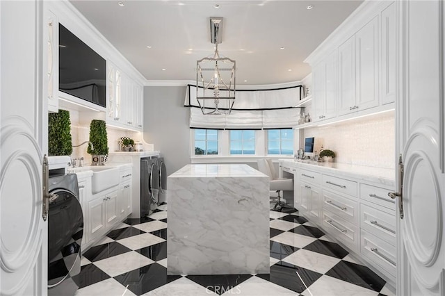 kitchen featuring sink, white cabinets, a notable chandelier, crown molding, and washer and clothes dryer