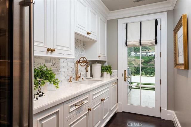 interior space featuring sink, crown molding, white cabinetry, high quality fridge, and decorative backsplash