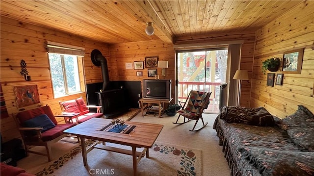 carpeted living room with wooden walls, wooden ceiling, and a wood stove