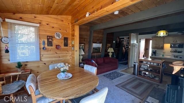 carpeted dining room featuring wooden ceiling and wood walls