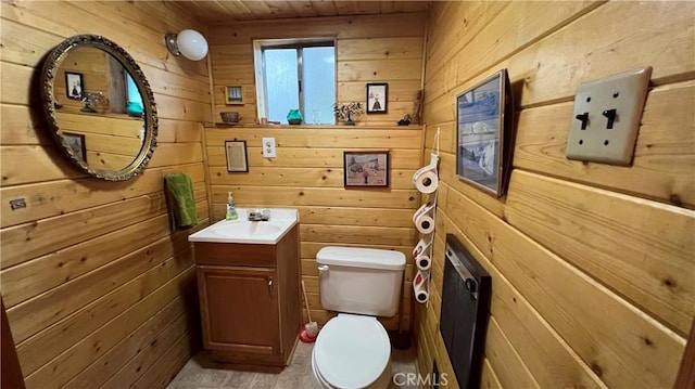 bathroom featuring vanity, wooden walls, and toilet