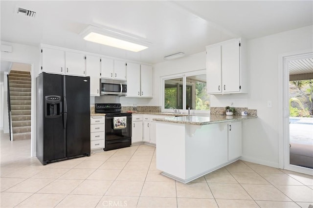 kitchen featuring plenty of natural light, black appliances, white cabinets, kitchen peninsula, and light stone countertops