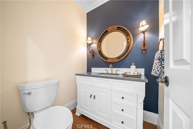 bathroom with toilet, baseboards, wood finished floors, and vanity