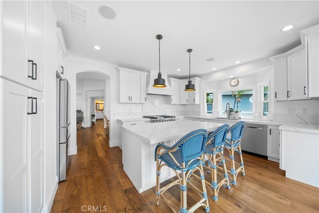 kitchen with arched walkways, a kitchen island, and white cabinetry