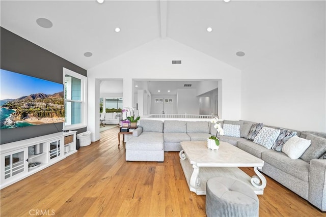 living room featuring high vaulted ceiling, light wood-type flooring, beam ceiling, and visible vents