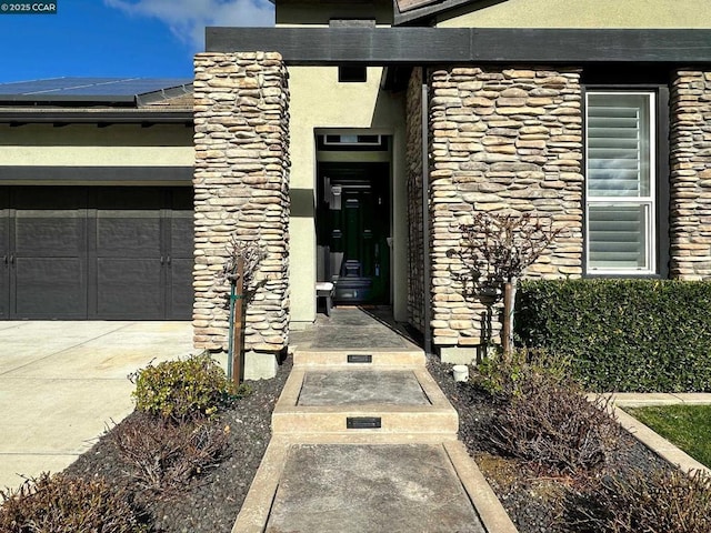 entrance to property featuring a garage and solar panels