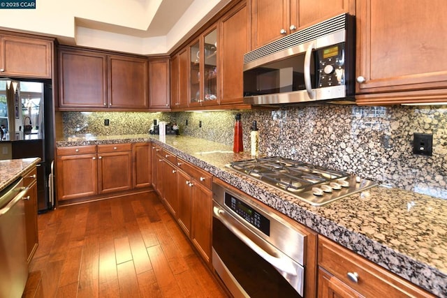 kitchen featuring dark hardwood / wood-style flooring, backsplash, and appliances with stainless steel finishes