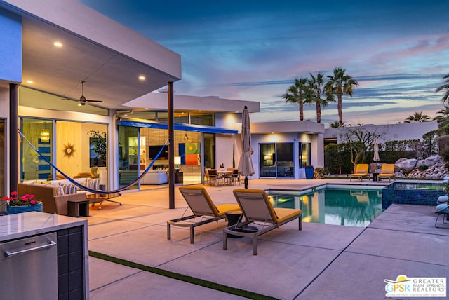 pool at dusk with an in ground hot tub, ceiling fan, an outdoor hangout area, and a patio area