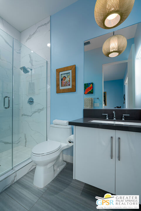 bathroom with walk in shower, vanity, and toilet