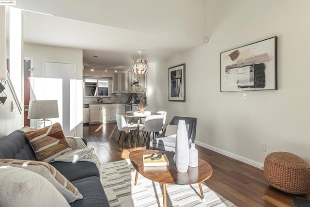 living room featuring dark wood-type flooring, track lighting, a chandelier, and sink