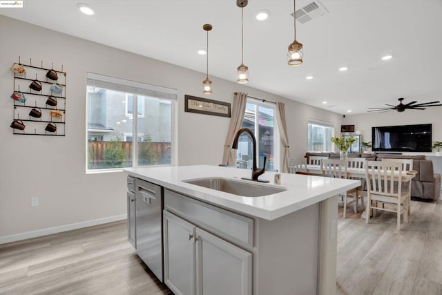 kitchen with sink, hanging light fixtures, dishwasher, an island with sink, and light hardwood / wood-style floors