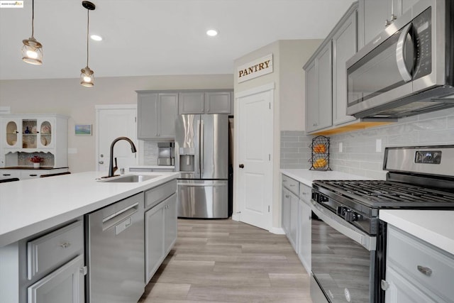 kitchen featuring appliances with stainless steel finishes, decorative light fixtures, sink, and gray cabinetry