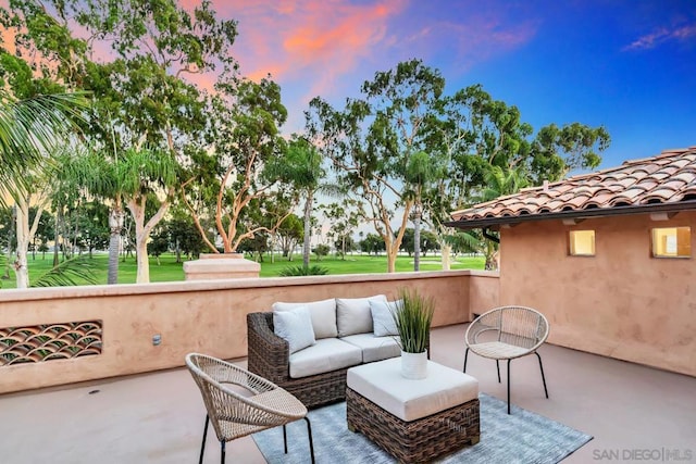 patio terrace at dusk featuring an outdoor living space and a lawn