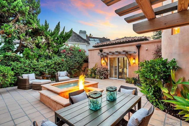 patio terrace at dusk featuring a pergola and an outdoor living space with a fire pit