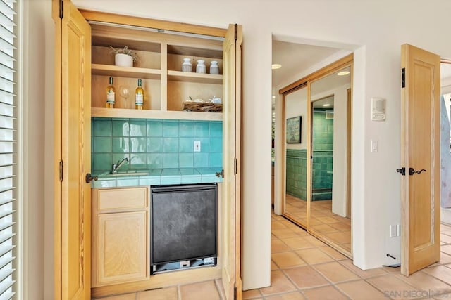 bar featuring tasteful backsplash, sink, fridge, tile counters, and light tile patterned floors