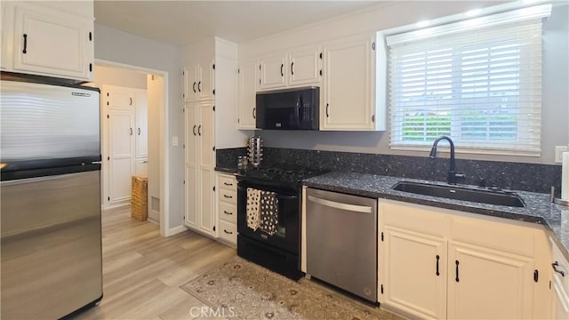 kitchen featuring sink, dark stone countertops, white cabinets, and black appliances