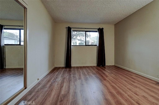 unfurnished room with light hardwood / wood-style flooring and a textured ceiling