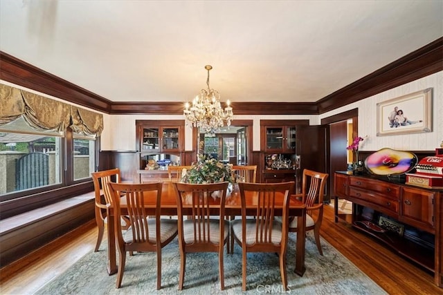 dining space with hardwood / wood-style flooring, a healthy amount of sunlight, and a notable chandelier