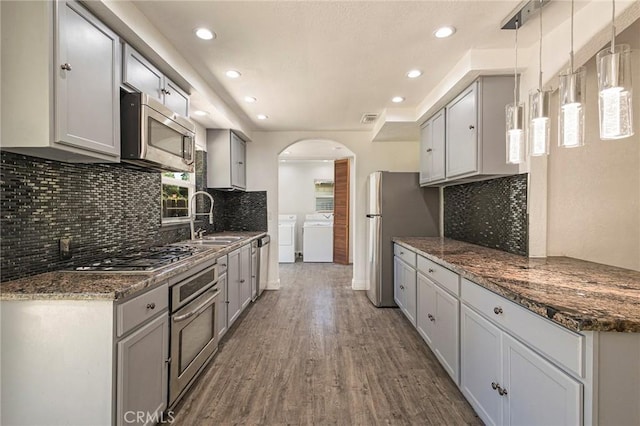 kitchen with sink, gray cabinetry, decorative light fixtures, appliances with stainless steel finishes, and washing machine and dryer