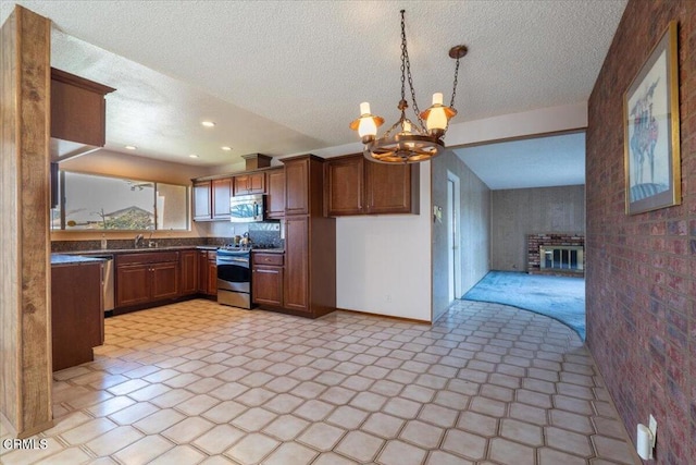 kitchen featuring an inviting chandelier, decorative light fixtures, sink, stainless steel appliances, and a textured ceiling