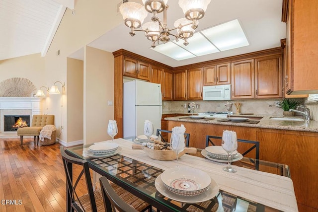 kitchen featuring sink, backsplash, a chandelier, hanging light fixtures, and white appliances