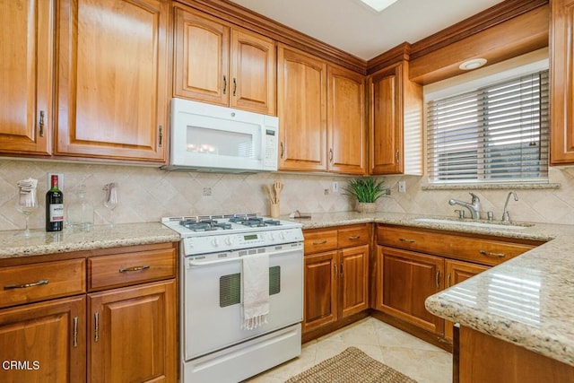 kitchen featuring light stone counters, white appliances, sink, and light tile patterned floors