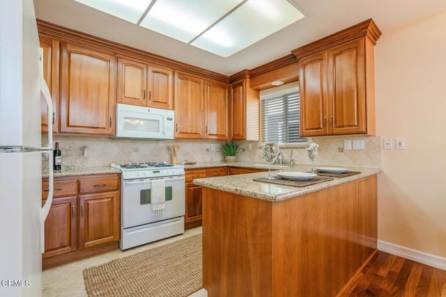 kitchen with light stone counters, white appliances, kitchen peninsula, and decorative backsplash