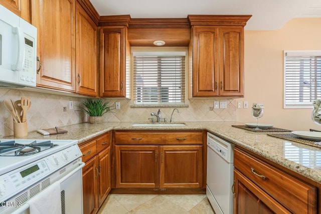 kitchen with sink, white appliances, light tile patterned floors, light stone counters, and decorative backsplash