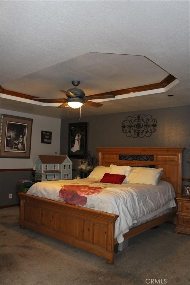 carpeted bedroom featuring ceiling fan and a raised ceiling