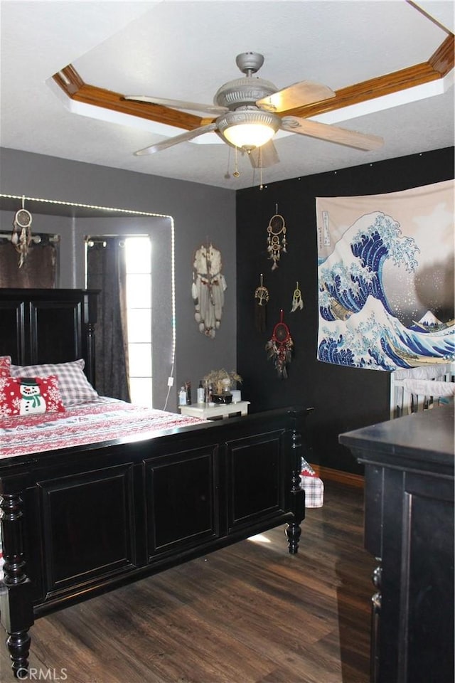 bedroom featuring a raised ceiling, dark hardwood / wood-style floors, and ceiling fan