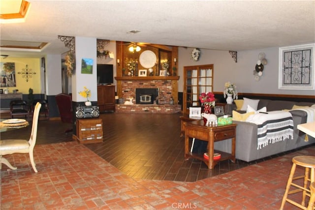 living room with hardwood / wood-style flooring, ceiling fan, a fireplace, and a textured ceiling