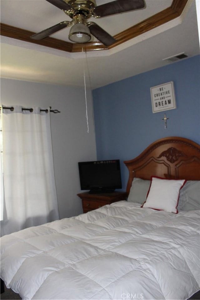 bedroom with ornamental molding, a raised ceiling, and ceiling fan