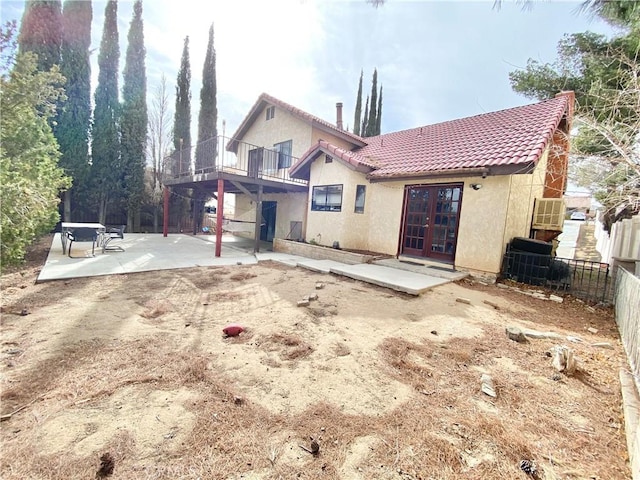 rear view of house featuring fence, a tiled roof, french doors, stucco siding, and a patio area