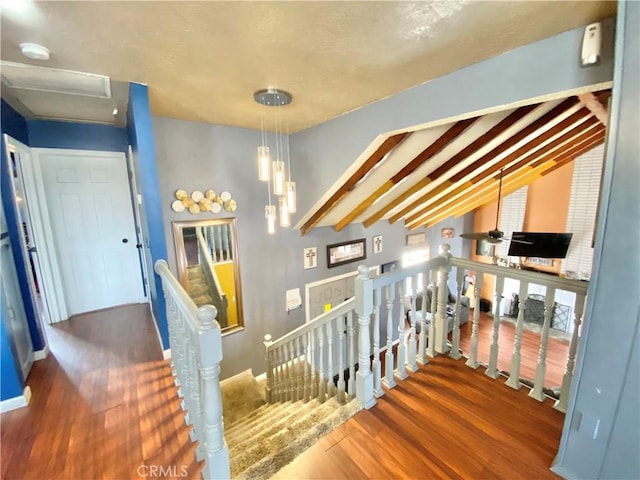 staircase featuring hardwood / wood-style flooring and vaulted ceiling with beams