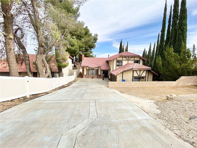 view of front of property featuring driveway, a tile roof, fence, and stucco siding