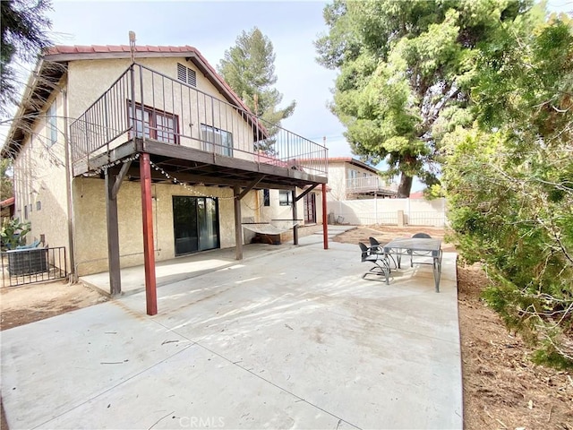 rear view of property with central air condition unit, stucco siding, outdoor dining space, a patio area, and fence