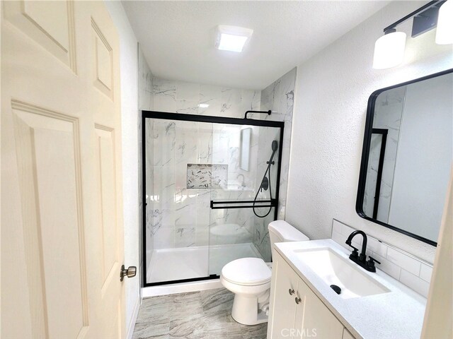 bathroom with toilet, vanity, and a shower with shower door