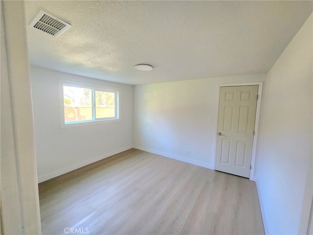 spare room with a textured ceiling and light wood-type flooring