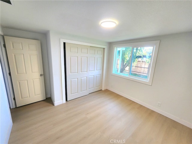 unfurnished bedroom with light wood-type flooring and a closet