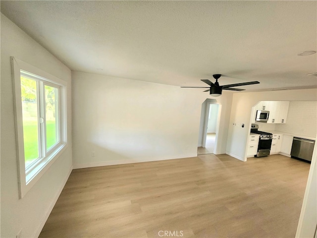 unfurnished living room with a textured ceiling, light hardwood / wood-style floors, and ceiling fan