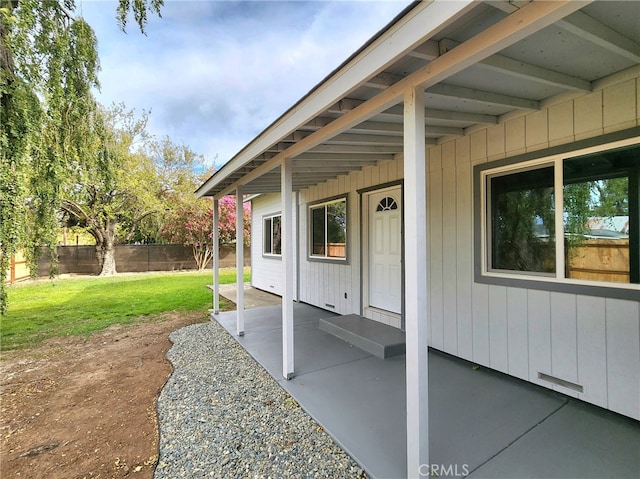 view of exterior entry featuring a lawn and a patio