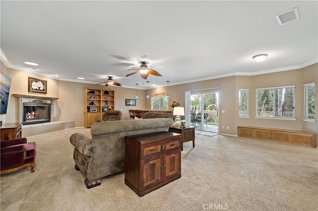 living room featuring ornamental molding, light colored carpet, ceiling fan, and a fireplace