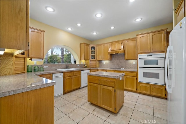 kitchen featuring light tile patterned flooring, backsplash, light stone counters, custom range hood, and white appliances