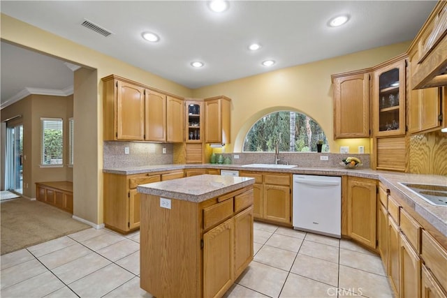 kitchen featuring sink, light tile patterned floors, dishwasher, backsplash, and a kitchen island