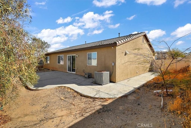 rear view of house with central AC unit and a patio