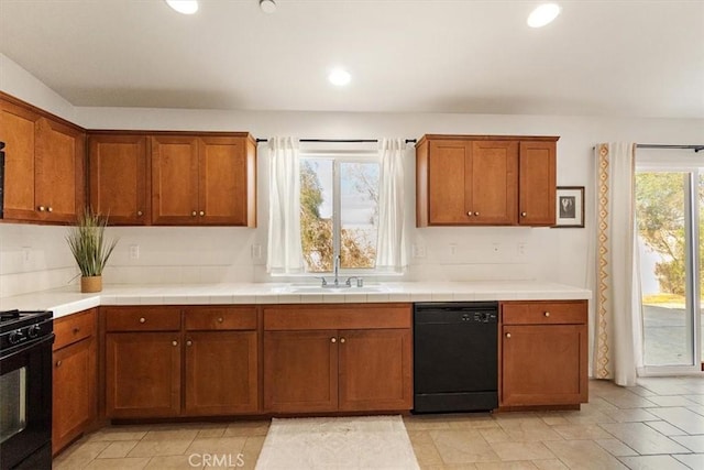 kitchen with sink, tile counters, and black appliances