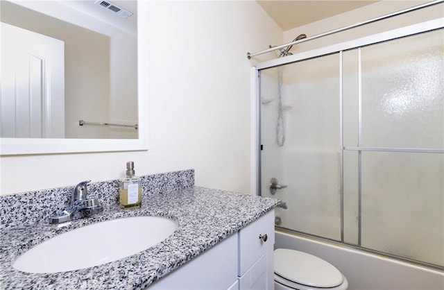 full bathroom featuring vanity, combined bath / shower with glass door, and toilet